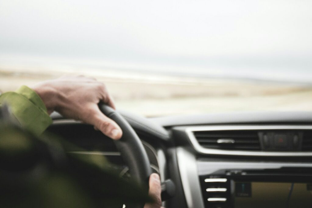 a person driving a car with a steering wheel