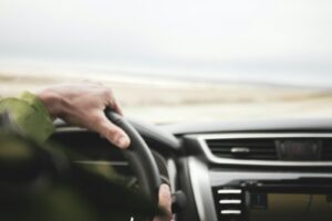 a person driving a car with a steering wheel
