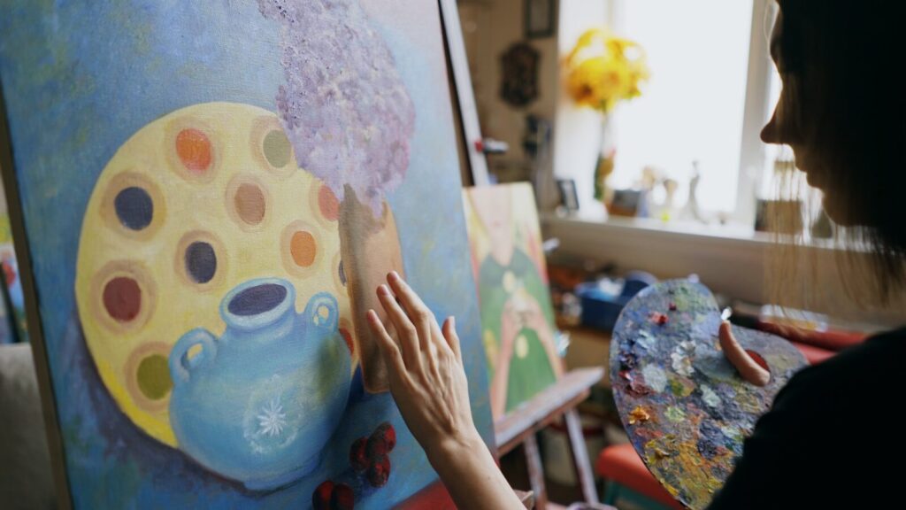 Artist painting a colorful abstract artwork on canvas.
